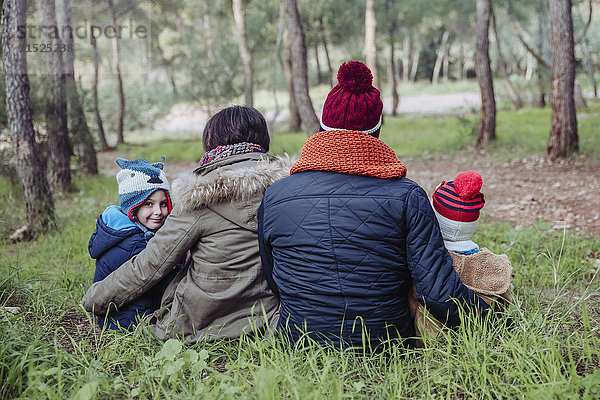 Rückansicht der im Wald sitzenden Familie