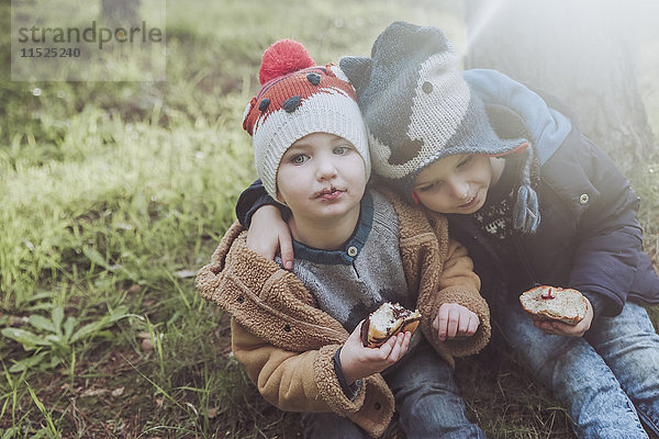 Zwei Jungen essen Berliner im Wald