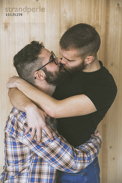 Schwules Paar vor der Holzwand küssen