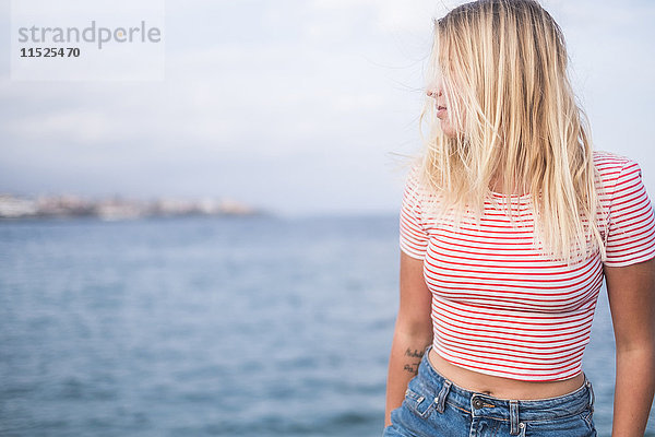 Blonde junge Frau vor dem Meer