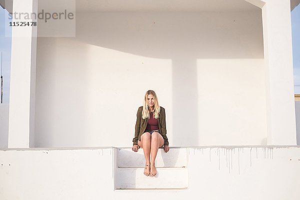 Spanien  Teneriffa  Portrait einer jungen blonden Frau auf einer Treppe sitzend