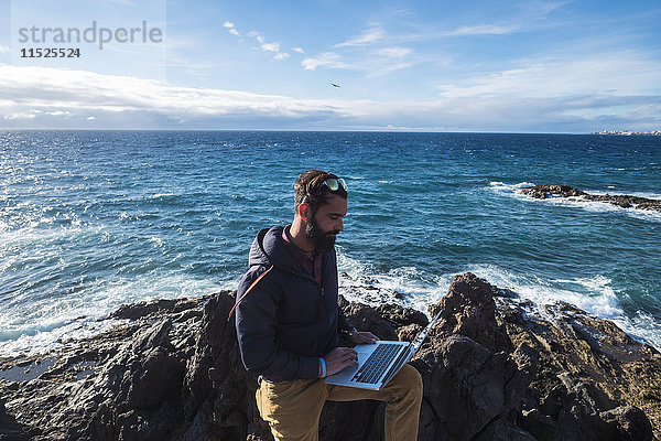 Spanien  Teneriffa  Mann mit Laptop vor dem Meer
