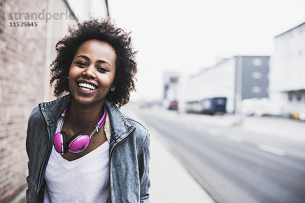 Portrait einer lächelnden jungen Frau mit Kopfhörer