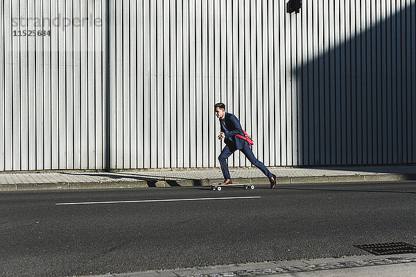 Jungunternehmer beim Skateboardfahren auf der Straße