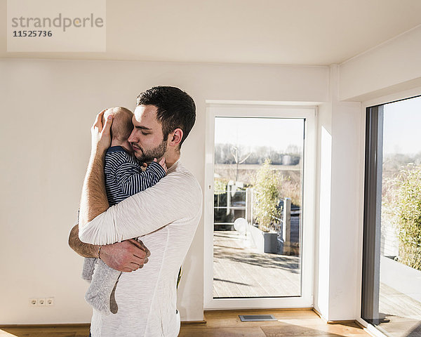 Vater hält und umarmt seinen kleinen Sohn  steht im gemütlichen Heim