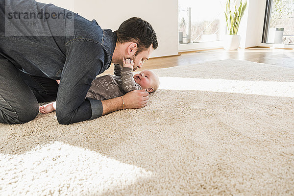 Vater und Sohn spielen zu Hause auf dem Teppich.