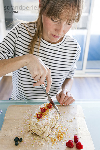 Junge Frau zerschneidet veganen Kuchen