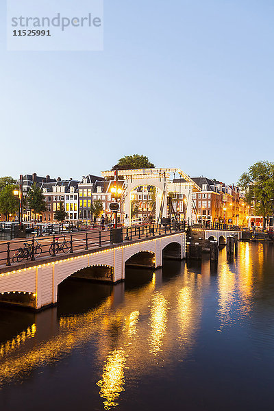 Niederlande  Amsterdam  Blick auf Magere Brug mit Amstel River im Vordergrund bei Abenddämmerung