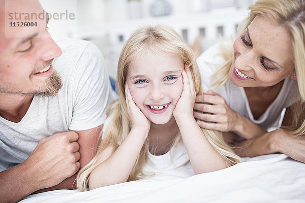 Porträt eines lächelnden Mädchens mit Eltern im Bett