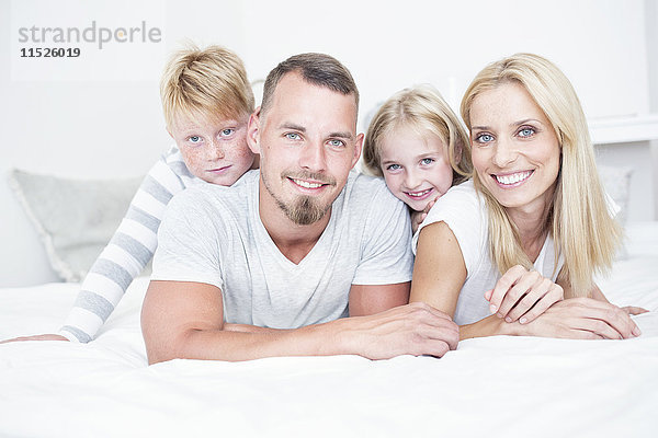 Porträt einer lächelnden Familie im Bett liegend