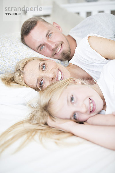 Porträt des lächelnden Mädchens und der im Bett liegenden Eltern
