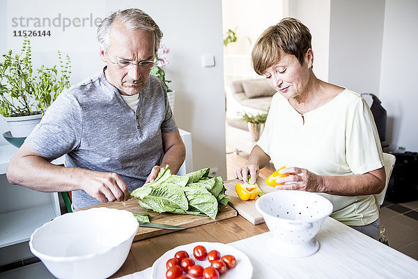 Seniorenpaar in der Küche bei der gemeinsamen Zubereitung von Salat