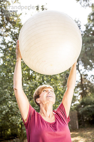 Seniorin beim Training mit Fitnessball im Freien