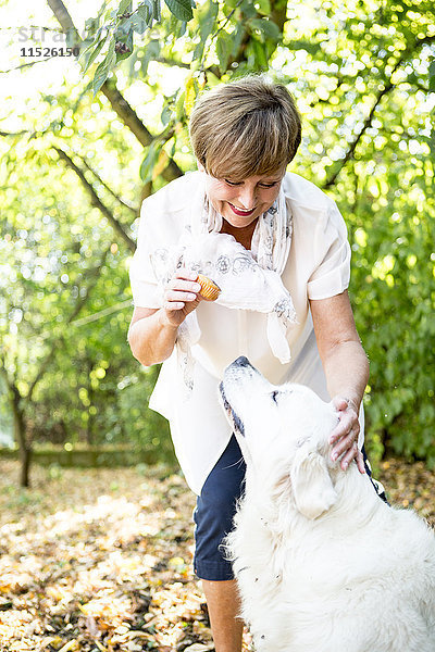 Seniorin mit Muffin und Streichelhund im Freien