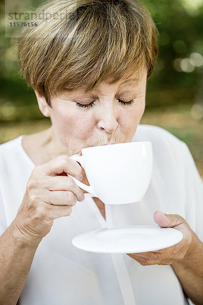 Seniorin trinkt eine Tasse Kaffee im Freien