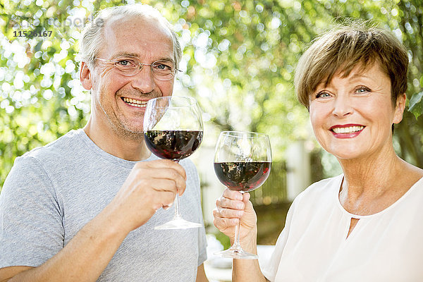 Glückliches Seniorenpaar bei einem Glas Rotwein im Freien