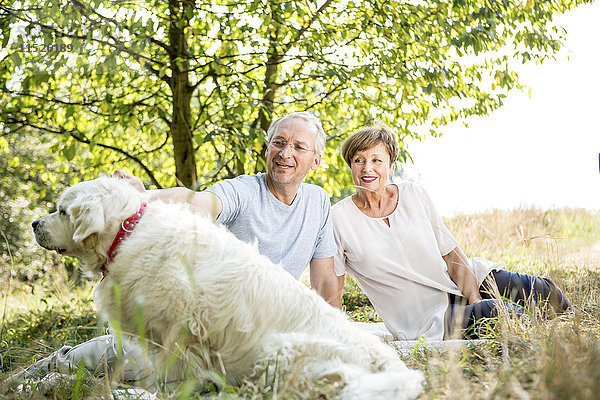 Seniorenpaar mit Hund auf der Wiese
