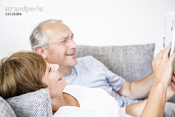 Seniorenpaar zu Hause auf der Couch liegend mit digitalem Tablett