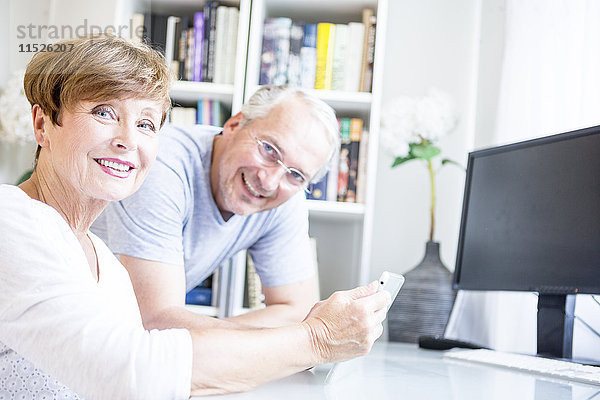 Seniorenpaar am Schreibtisch mit digitalem Tablett
