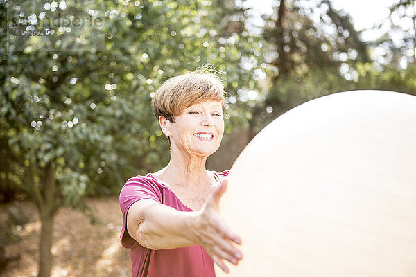 Seniorin beim Training mit Fitnessball im Freien