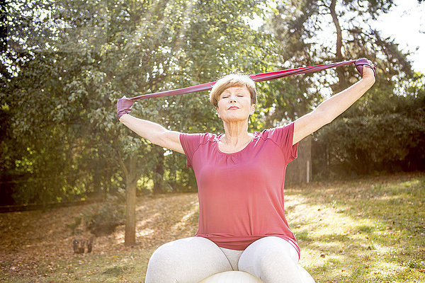 Seniorin beim Training mit Widerstandsband im Freien