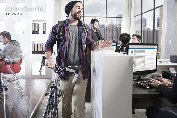 Lässiger Mann mit Fahrrad im modernen Büro
