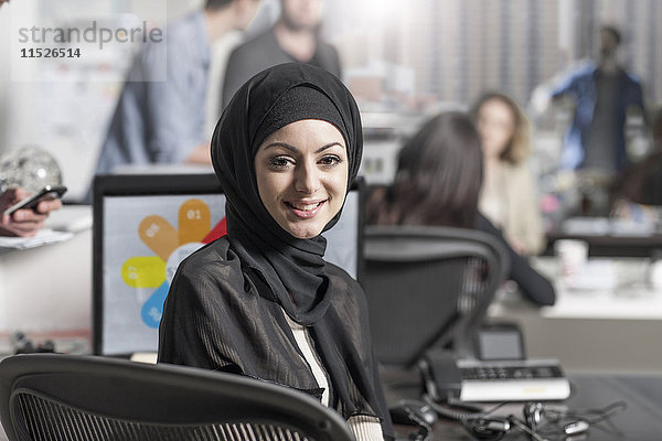 Porträt einer lächelnden jungen Frau mit Hijab im Büro