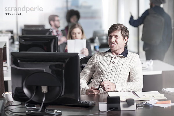 Lächelnder Mann am Schreibtisch im Büro