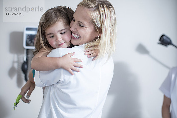 Kinderarzt umarmt ein kleines Mädchen