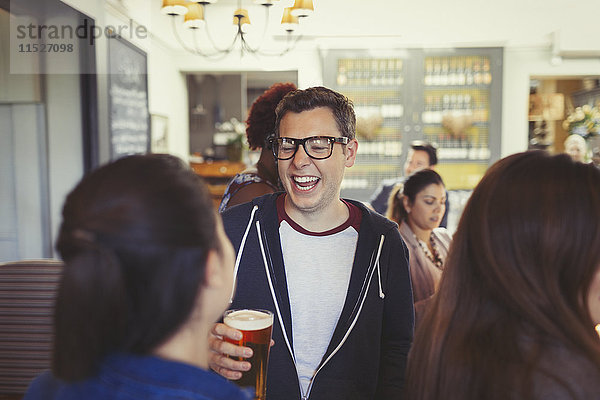 Mann lacht und trinkt Bier mit Freunden an der Bar