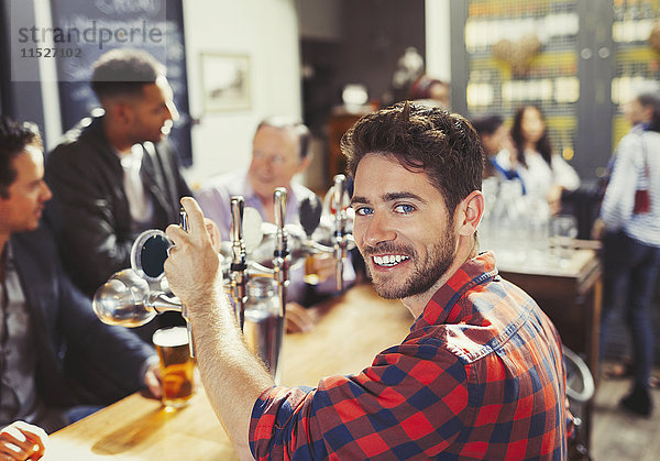 Portrait lächelnder  selbstbewusster Barkeeper serviert Bier an der Bar.