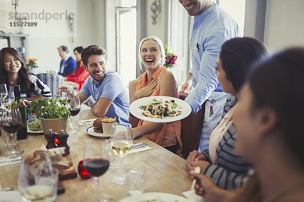Kellner serviert Salat an eine Frau  die mit Freunden am Restauranttisch speist.