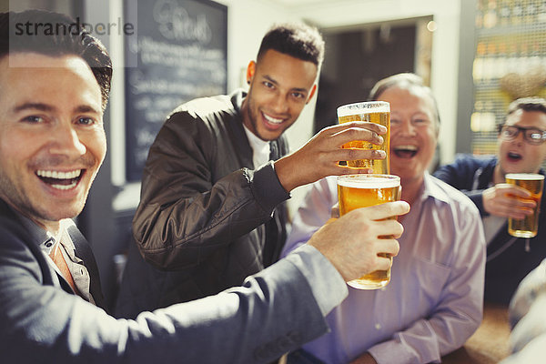 Enthusiastische Männer Freunde toasten Biergläser an der Bar