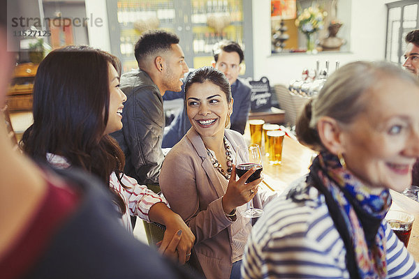 Lächelnde Frauenfreunde beim Reden und Weintrinken in der Bar
