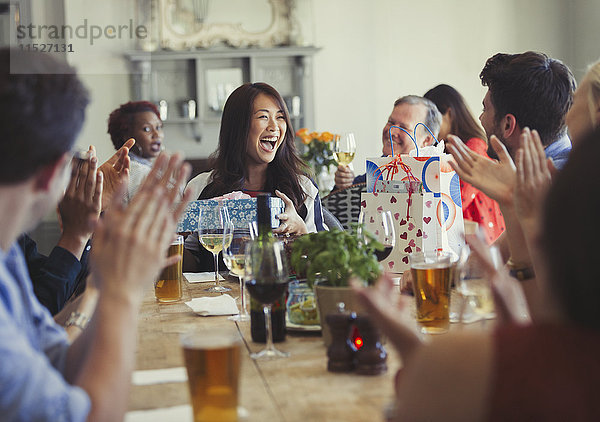 Freunde klatschen für eine glückliche Frau  die am Restauranttisch Geburtstag feiert.
