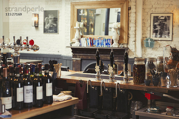 Weinflaschen und Zapfhahngriffe hinter der Bar im leeren Pub