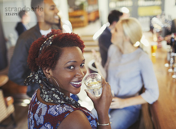 Portrait lächelnde Frau trinkt Wasser und redet mit Freunden an der Bar