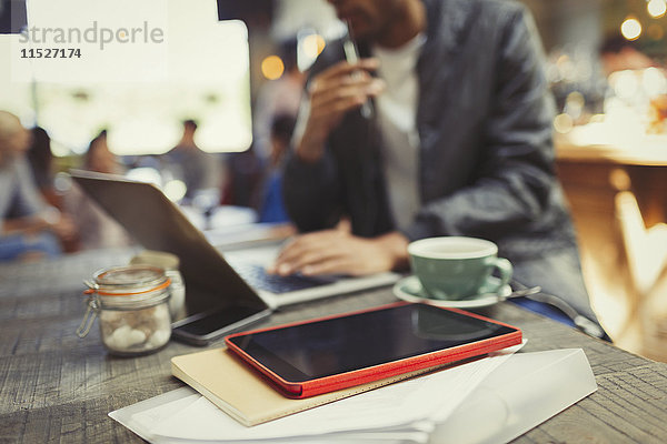 Kreativer Geschäftsmann bei der Arbeit am Laptop hinter dem digitalen Tablett im Café