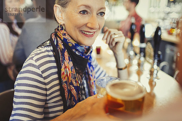 Seniorin trinkt Bier an der Bar