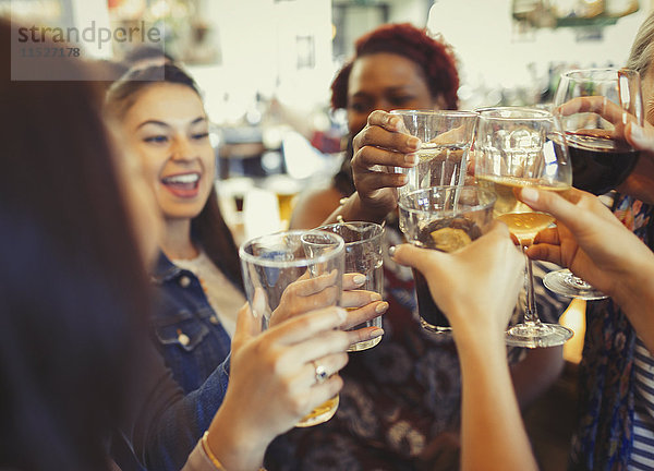 Begeisterte Frauen feiern  rösten Bier und Weingläser an der Bar