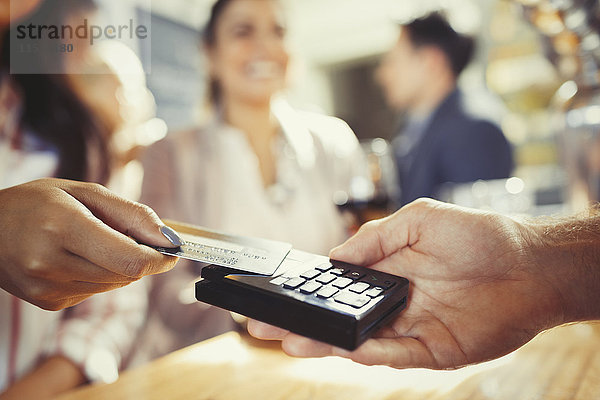 Frau mit Kreditkarte zahlender Barkeeperin mit kontaktloser Bezahlung an der Bar