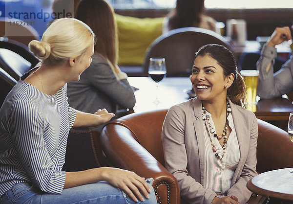 Lächelnde Frauen sprechen in der Bar