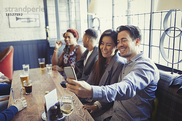 Lächelndes Paar nimmt Selfie mit Fotohandy am Tisch in der Bar mit.