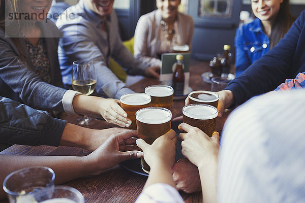 Freunde greifen nach Biergläsern auf dem Stehtisch