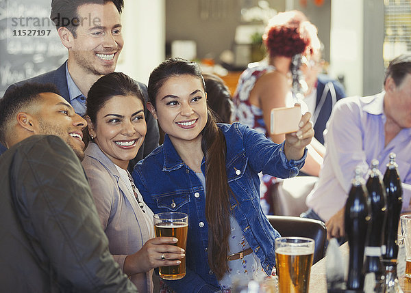 Verspielte Freunde trinken Bier und nehmen Selfie mit Fotohandy an der Bar.