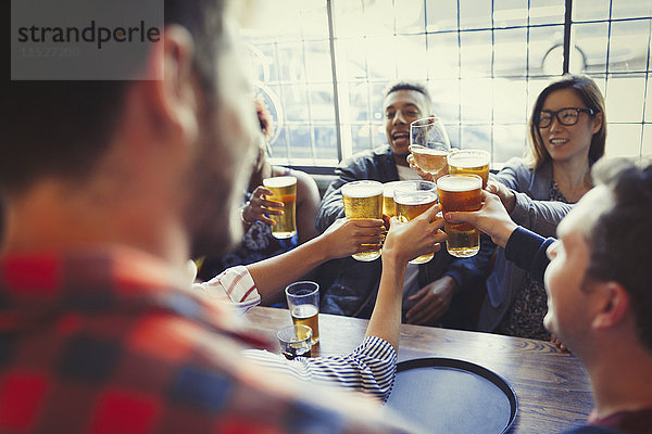 Freunde feiern  rösten Bierglas am Stehtisch