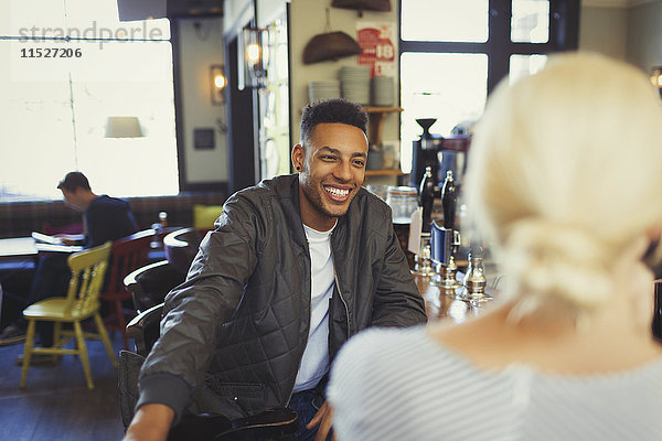 Lächelnder Mann im Gespräch mit Frau in der Bar