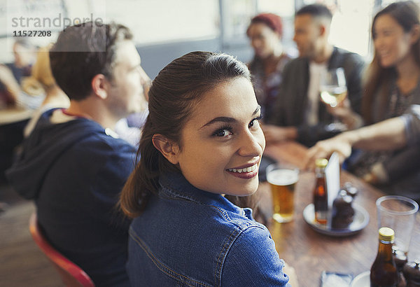 Portrait lächelnde Frau beim Biertrinken mit Freunden am Tisch in der Bar