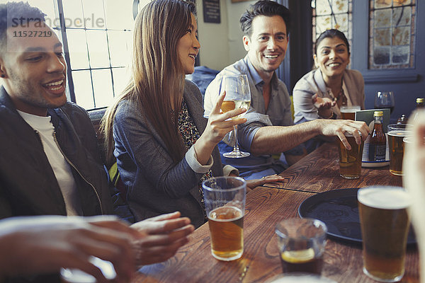 Freunde  die Bier und Wein trinken und bei Tisch in der Bar reden.