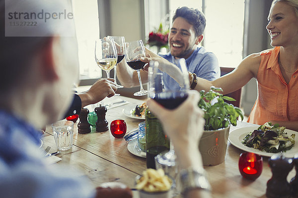 Lächelnde Freunde beim Feiern  Trinken von Weingläsern am Restauranttisch